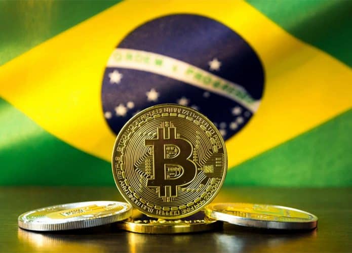 Moedas de bitcoin com bandeira do Brasil ao fundo