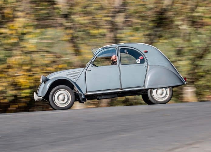 Homem dirigindo Citroën 2CV numa rua