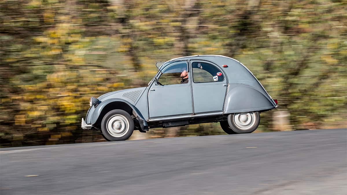 Homem dirigindo Citroën 2CV numa rua