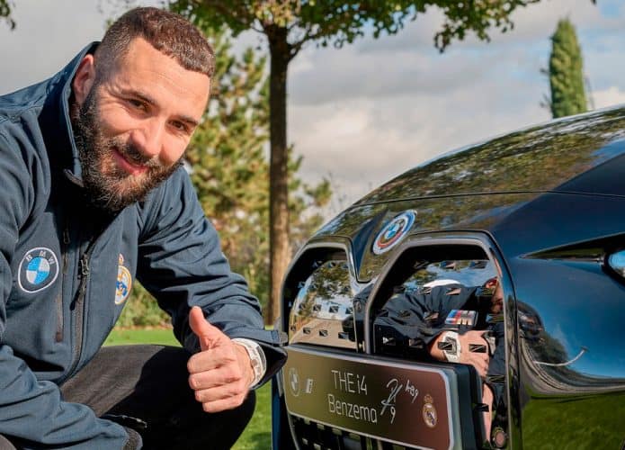 Jogador Karim Benzema agachado em frente BMW i4 M50