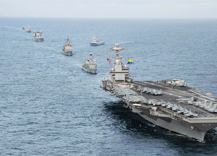 Maior porta-aviões do mundo navegando pelo oceano com outras embarcações militares o seguindo