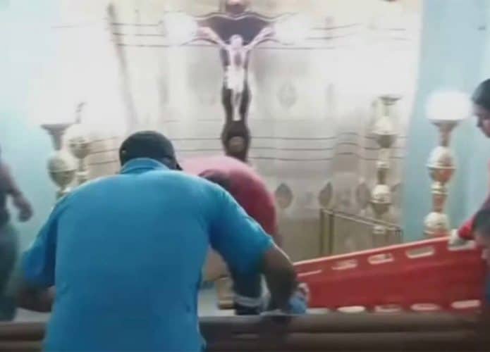 Familiares de idosa e paramédicos em volta do seu caixão durante velório