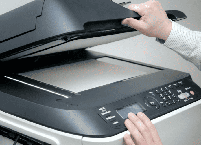 Imagem mostrando impressora de escritório com usuário fazendo alguma função de scanner