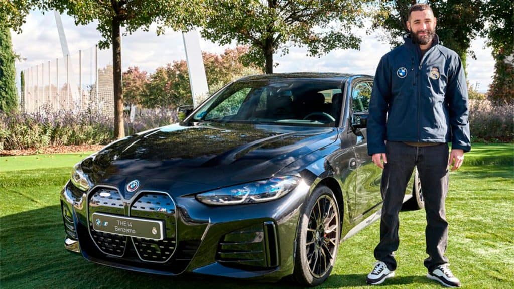 Jogador Karim Benzema agachado ao lado de BMW i4 M50
