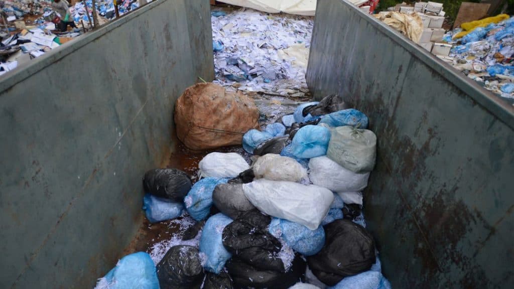 Visão de cima de uma caçamba de lixo despejando em lixão
