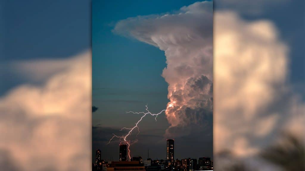 Raio saindo de nuvem cumulonimbus em cima de uma cidade