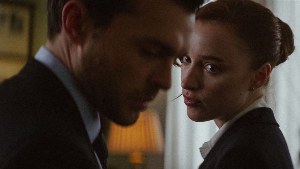 Imagem mostra cena do filme Fair Play em que os atores Alden Ehrenreich (de perfil, em primeiro plano) e Phoebe Dynevor (olhando para ele) interpretam um casal