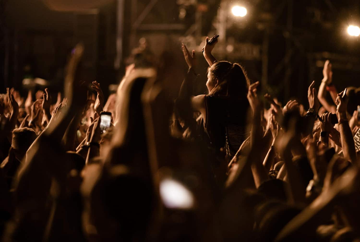 multidao-de-pessoas-com-bracos-levantados-se-divertindo-no-festival-de-musica-a-noite