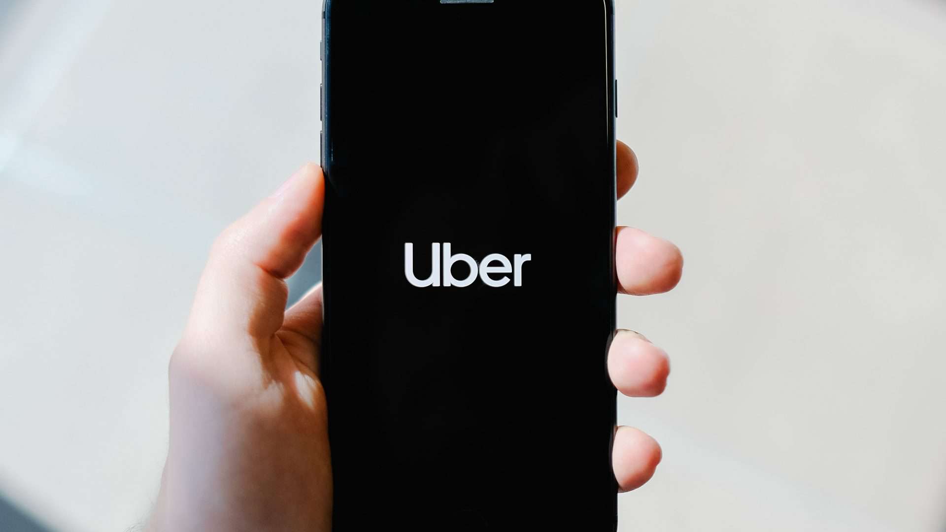 Mão segurando celular com a palavra Uber escrita na tela