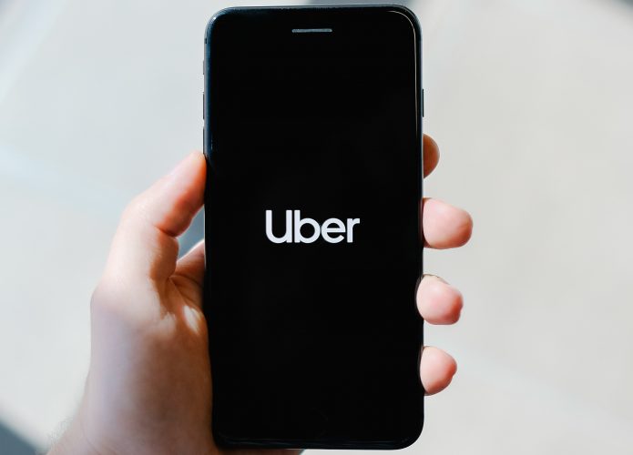 Mão segurando celular com a palavra Uber escrita na tela