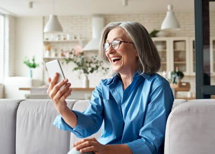 Mulher rindo para tela de celular em conversa com alguém on-line
