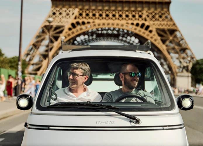 Homens dirigindo Microlino em Paris, perto da Torre Eiffel