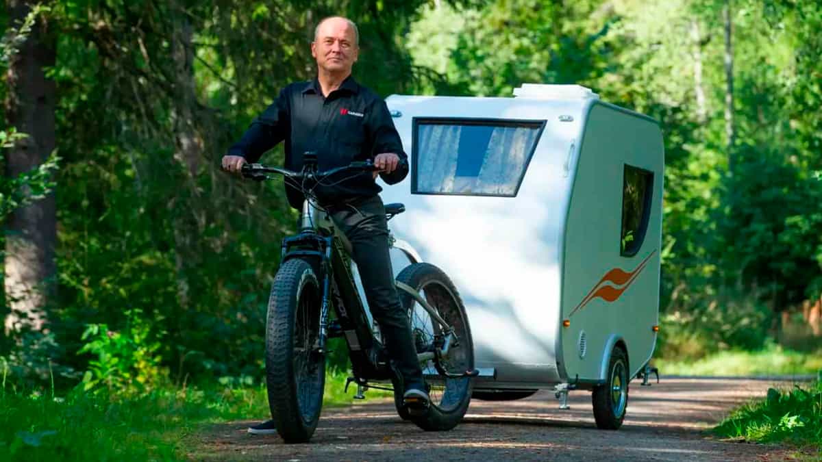 Homem andando em bicicleta elétrica puxando mini trailer