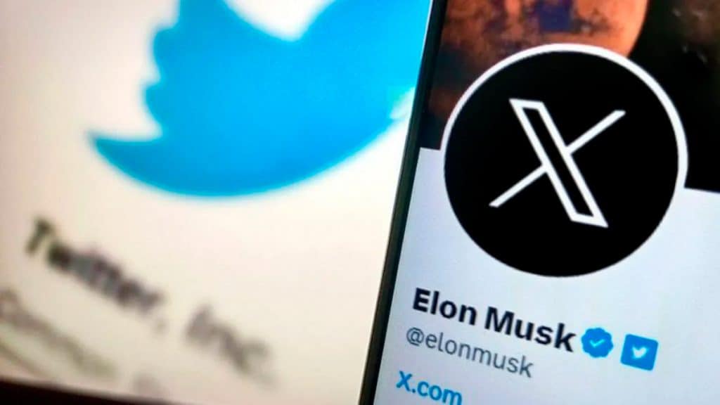 Celular com a página de Elon Musk aberta no Twitter e, ao fundo, a logomarca do Twitter numa tela de computador
