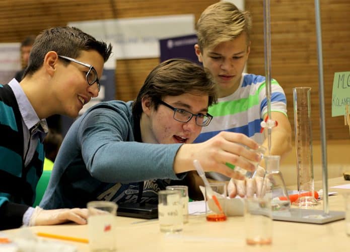 Três estudantes jovens conduzindo experimento científico