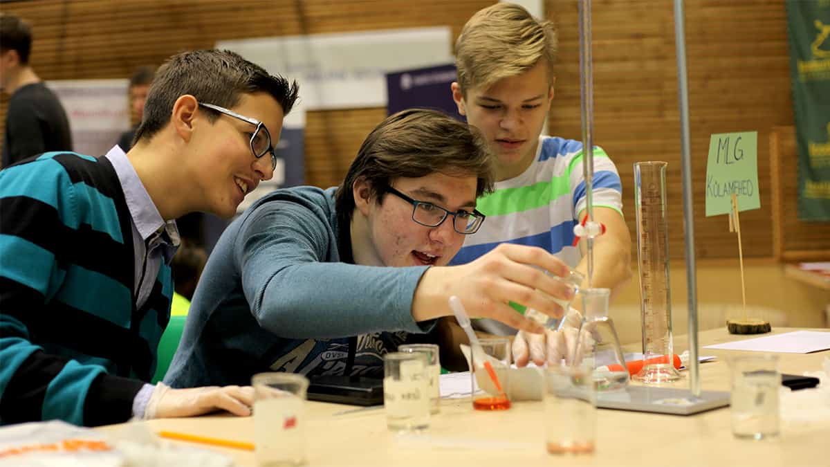 Três estudantes jovens conduzindo experimento científico