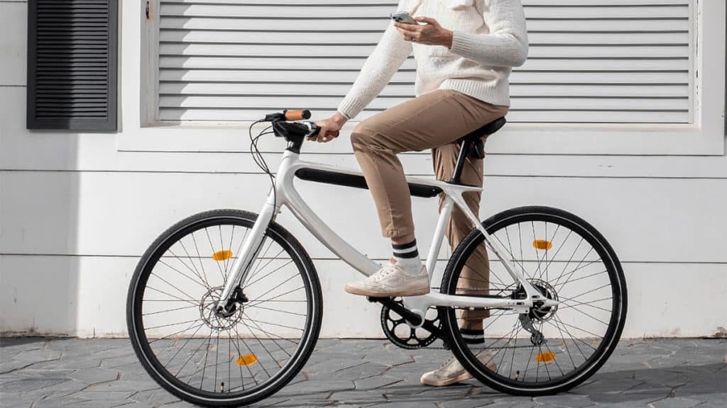 Homem sentado na e-bike Chord, da Urtopia, mexendo no celular