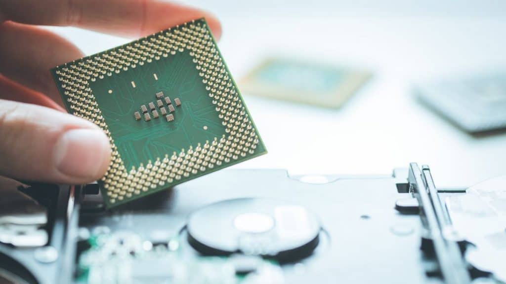 Pessoa segurando uma placa parecida com algum hardware de algum microcomputador