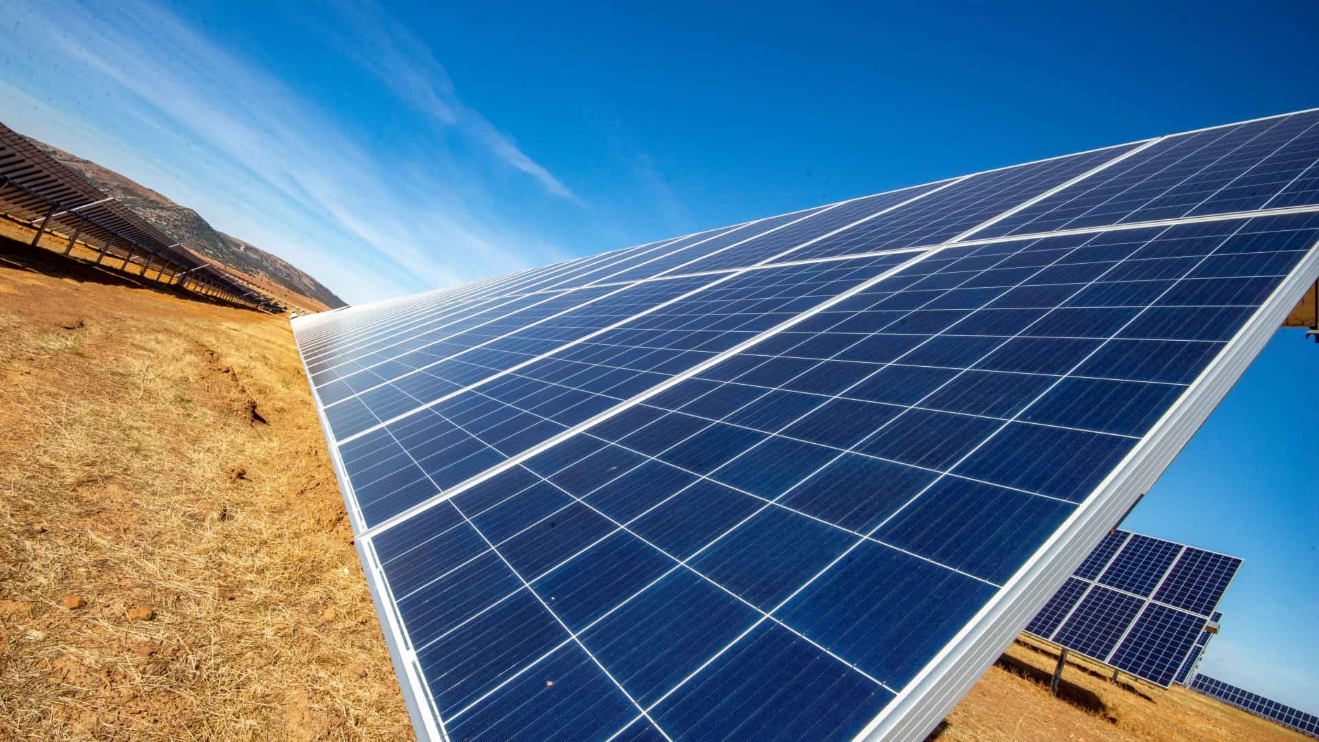 Imagem mostra paineis de energia solar com luz do sol refletindo neles