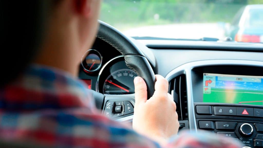 Homem dirigindo carro com GPS embutido no painel ligado
