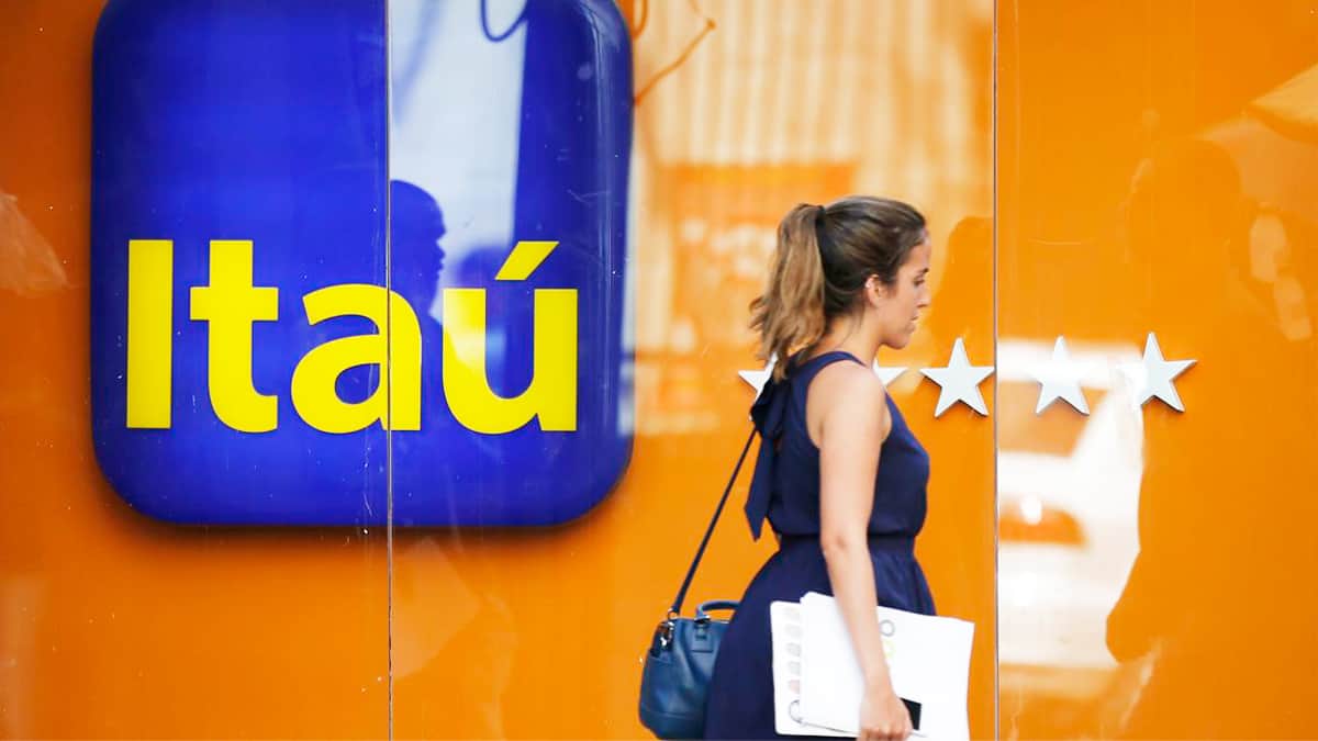 Mulher passando na frente de prédio do Itaú