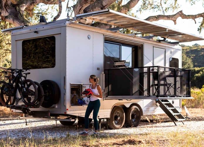 Casal em volta de trailer elétrico HD30 da Living Vehicle estacionado sob uma árvore