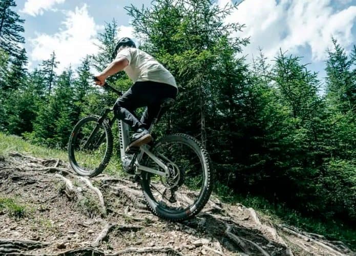 Homem subindo barranco montado numa Ekano 2 AL, a Mountain bike elétrica da Propain