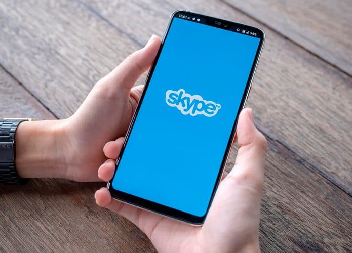 Pessoa segurando celular com logomarca do Skype