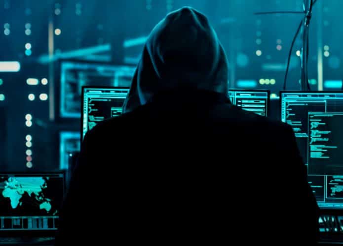 Hacker de costas rodeado por equipamentos