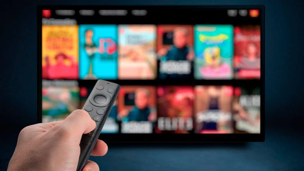 Pessoa apontando controle para TV com serviço de streaming aberto