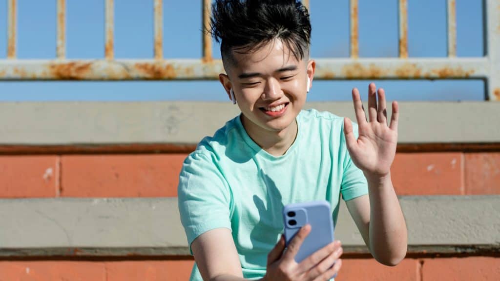 Menino acenando para celular em dia ensolarado