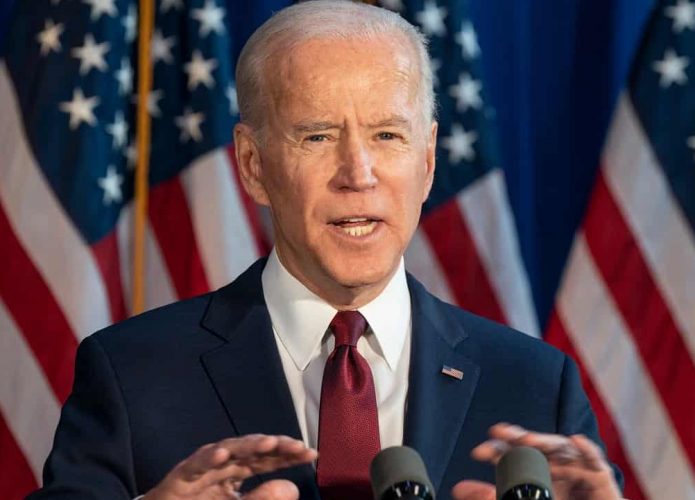 Joe Biden enquanto presidente dos Estados Unidos durante discurso em palanque em frente bandeiras do país