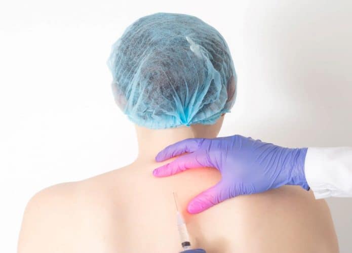 Médico aplica injeção nas costas de paciente