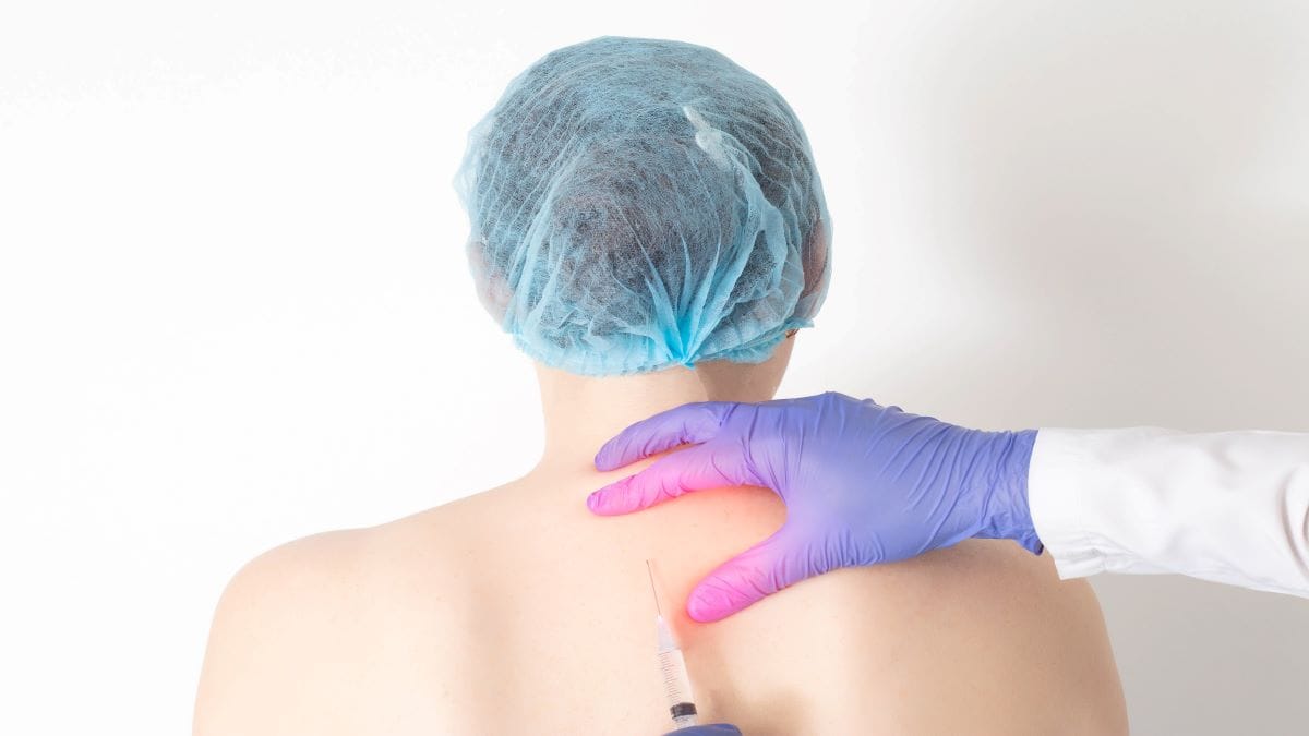 Médico aplica injeção nas costas de paciente