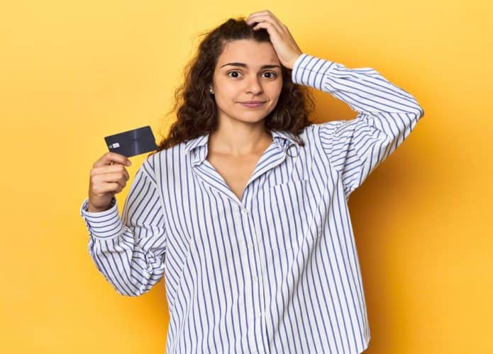 mulher com a mão na cabeça e cartão de crédito na mão