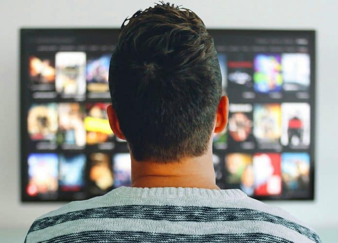 Homem em frente a uma tela de streaming de vídeo