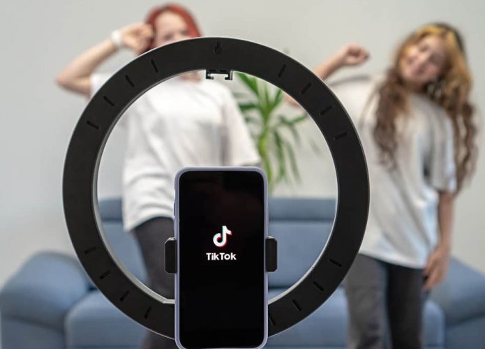 Duas meninas dançando enquanto celular com TikTok aberto e encaixado numa ring light grava