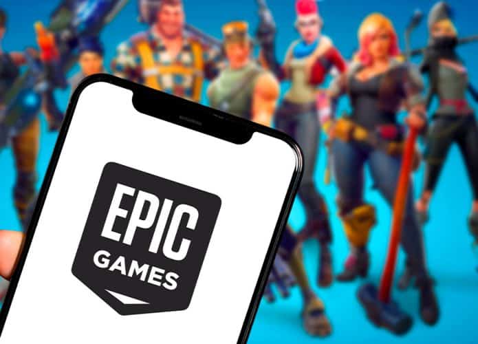 Pessoa segurando celular com logotipo da Epic Games e personagens de Fortnite ao fundo