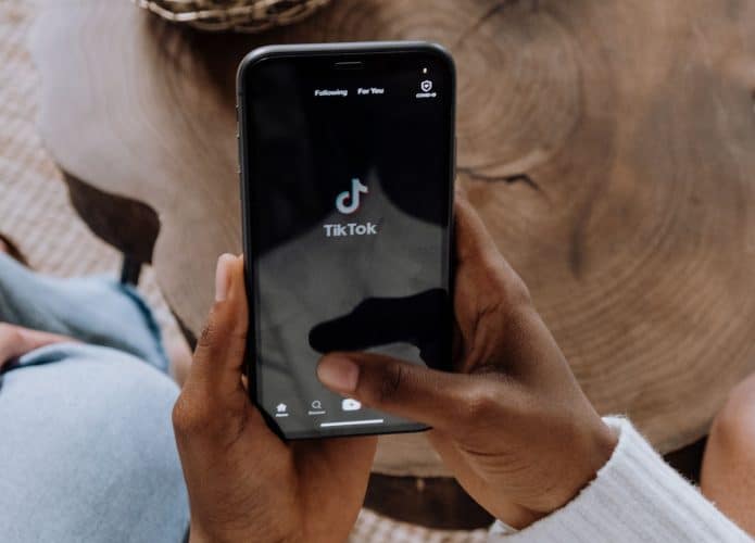Pessoa segurando celular enquanto o aplicativo do TikTok abre
