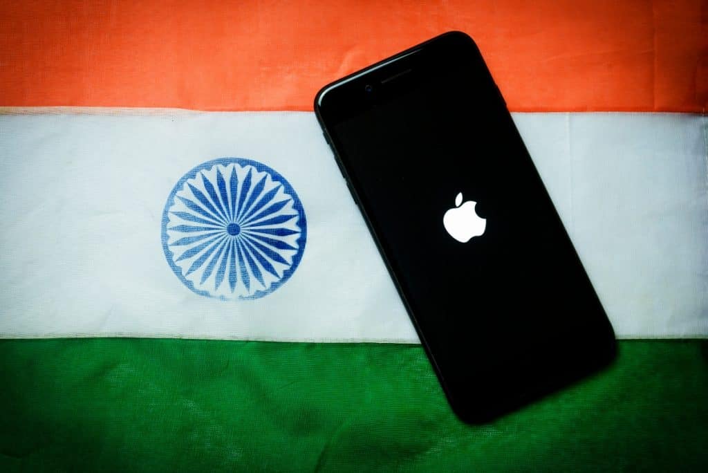 Logotipo da Apple na tela do iPhone com bandeira da Índia ao fundo
