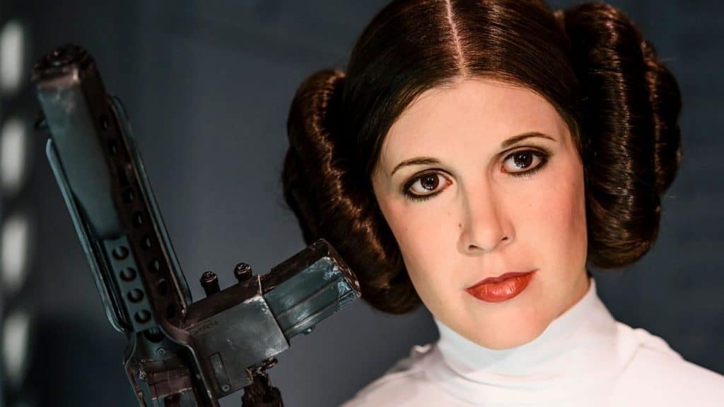 A atriz Carrie Fischer posa com arma em cena do filme Star Wars