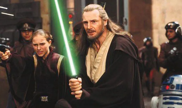 O ator Liam Neeson segura sabre de luz em cena de filme Star Wars