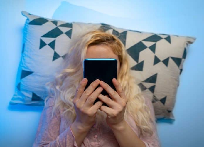 mulher olhando celular deitada