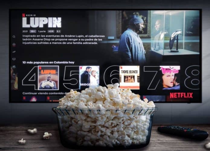 TV com pipoca na mesa e sobre a tela a imagem de Lupin na Netflix