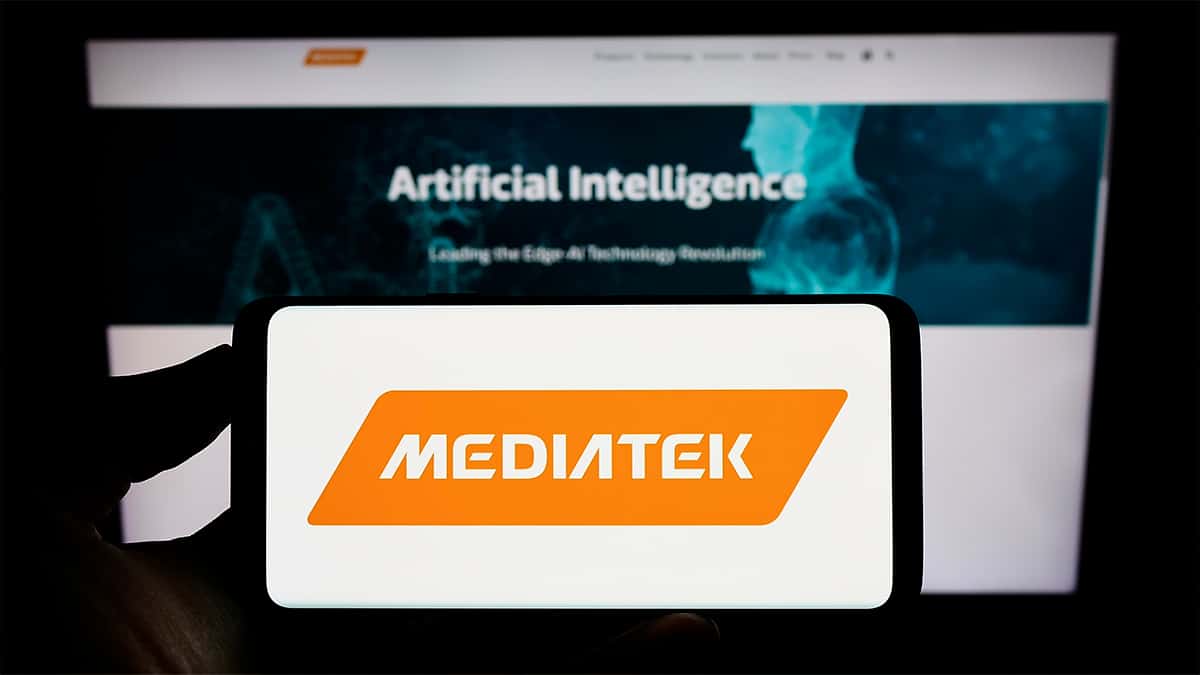 Celular com logotipo da MediaTek na tela colocado em frente tela de computador com página sobre IA aberta