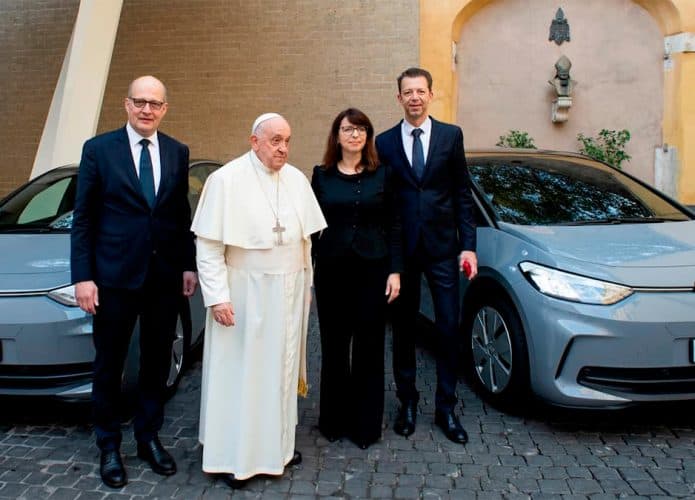 Papa e autoridades da Volkswagen em frente dois carros elétricos da montadora