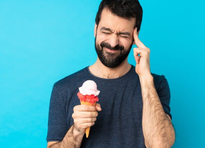homem com dor de cabeça e segurando um sorvete