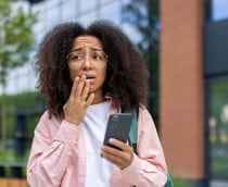 Mulher preocupada com o celular na mão