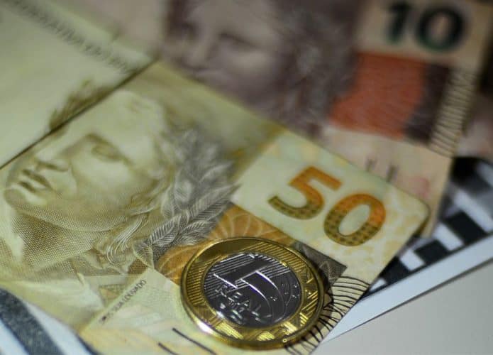 Dinheiro em notas e moedas sobre mesa