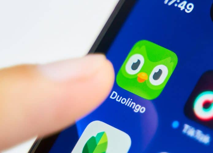 Pessoa com dedo sobre ícone do aplicativo do Duolinguo num iPhone